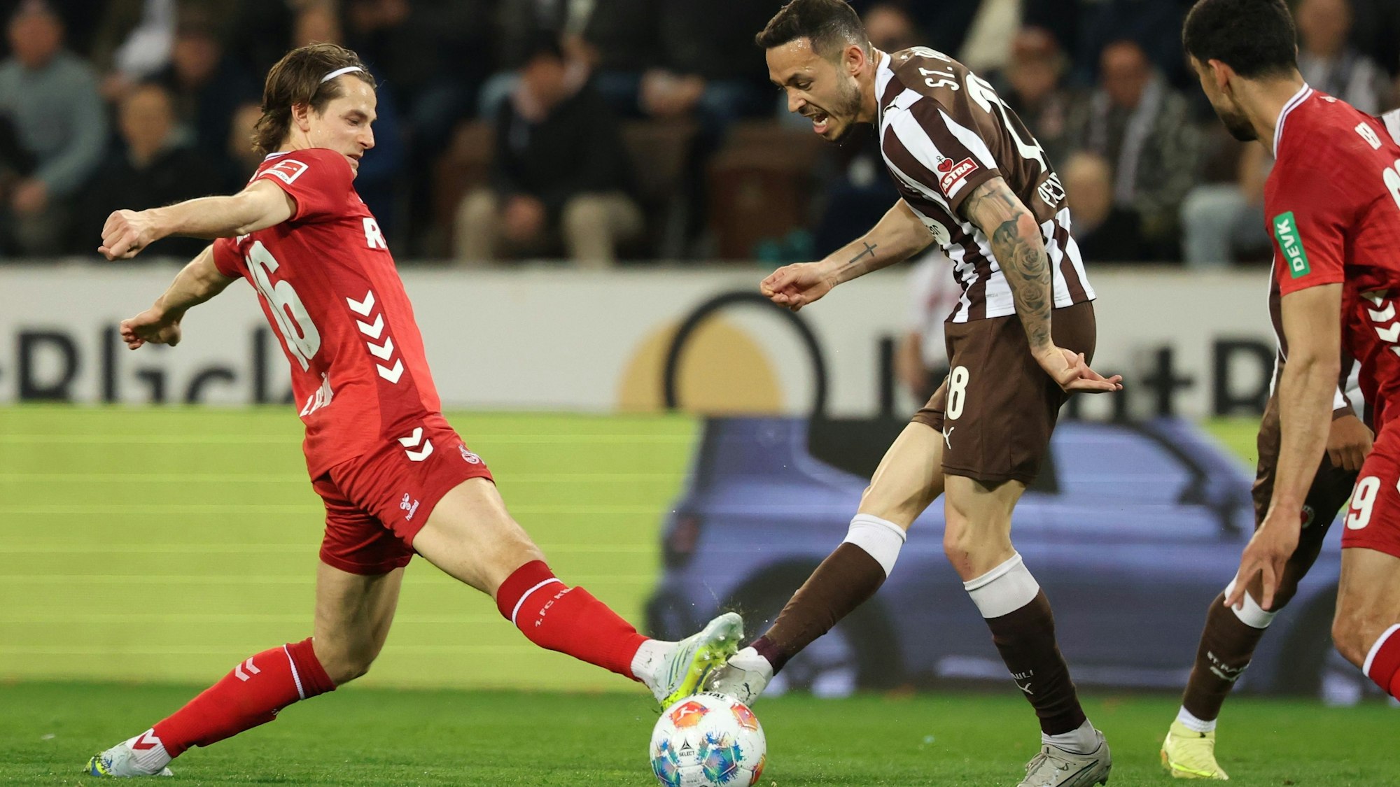 17.04.2026, Hamburg: Fußball, Männer: Bundesliga, FC St. Pauli - 1. FC Köln, 30. Spieltag, Millerntor-Stadion. Jakub Kamiński (l, 1. FC Köln) und Mathias Pereira Lage (M, FC St. Pauli) kämpfen um den Ball. Foto: Christian Charisius/dpa - WICHTIGER HINWEIS: Gemäß den Vorgaben der DFL Deutsche Fußball Liga bzw. des DFB Deutscher Fußball-Bund ist es untersagt, in dem Stadion und/oder vom Spiel angefertigte Fotoaufnahmen in Form von Sequenzbildern und/oder videoähnlichen Fotostrecken zu verwerten bzw. verwerten zu lassen. +++ dpa-Bildfunk +++