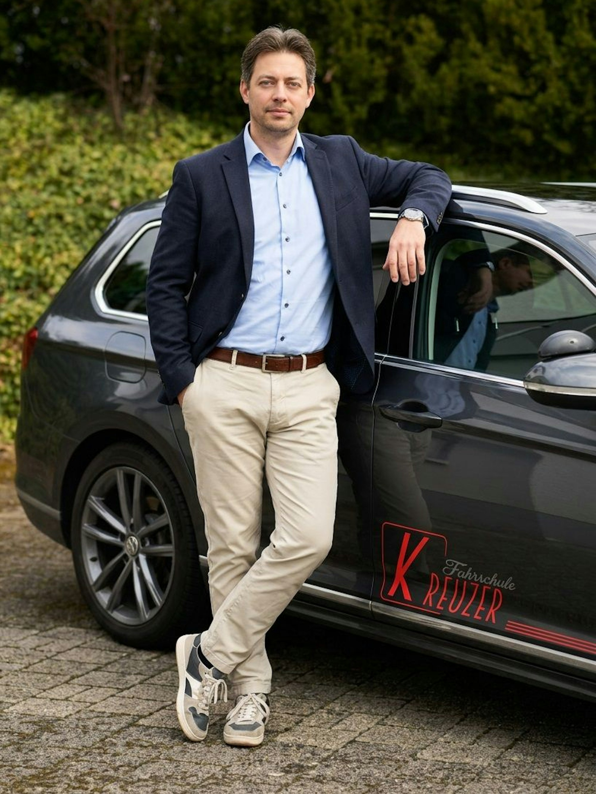 Christian Kreuzer steht an einem Fahrschulauto.