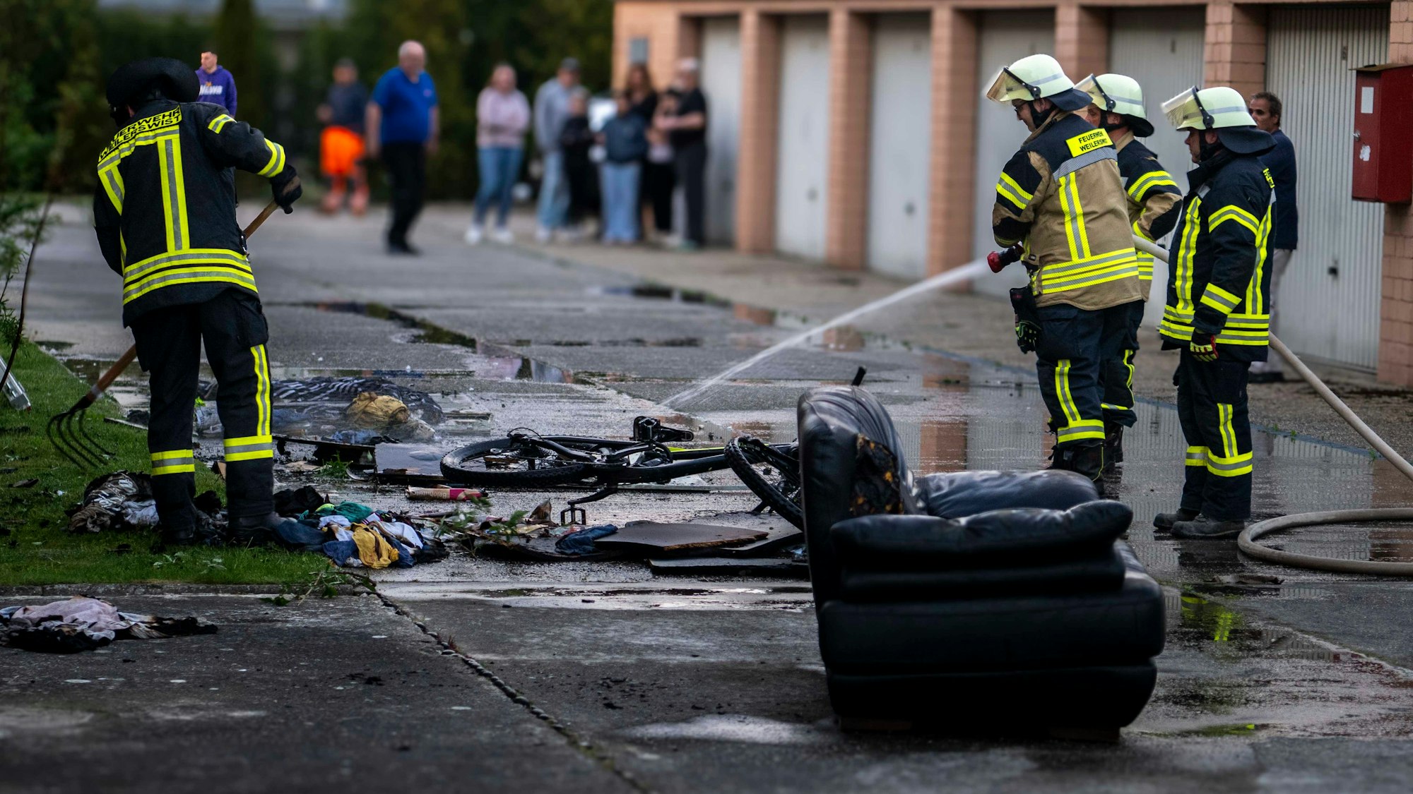 Das Bild zeigt Feuerwehrleute, die gerade ein Mountainbike löschen.
