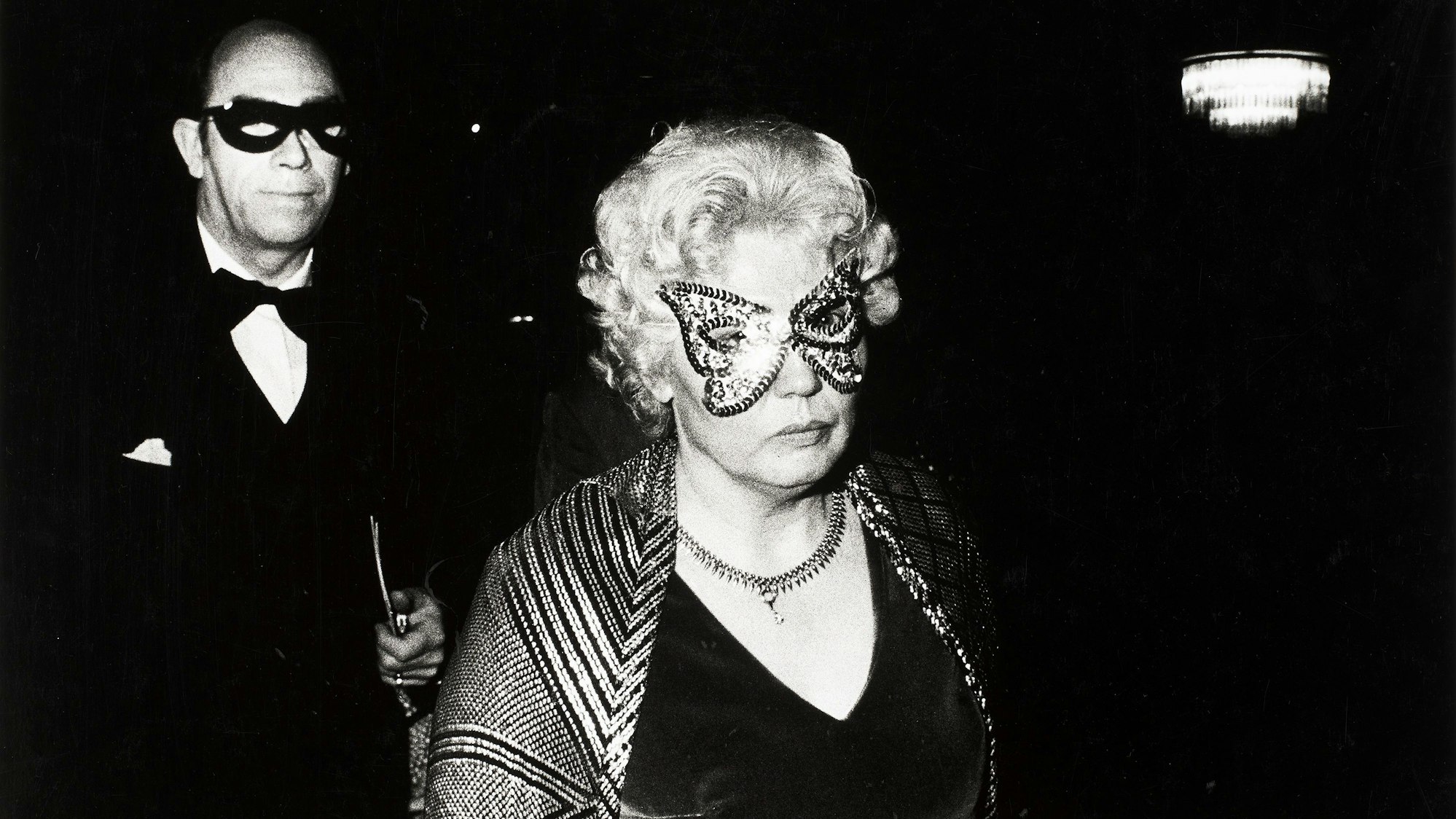 Ein maskiertes Paar schaut in die Kamera.