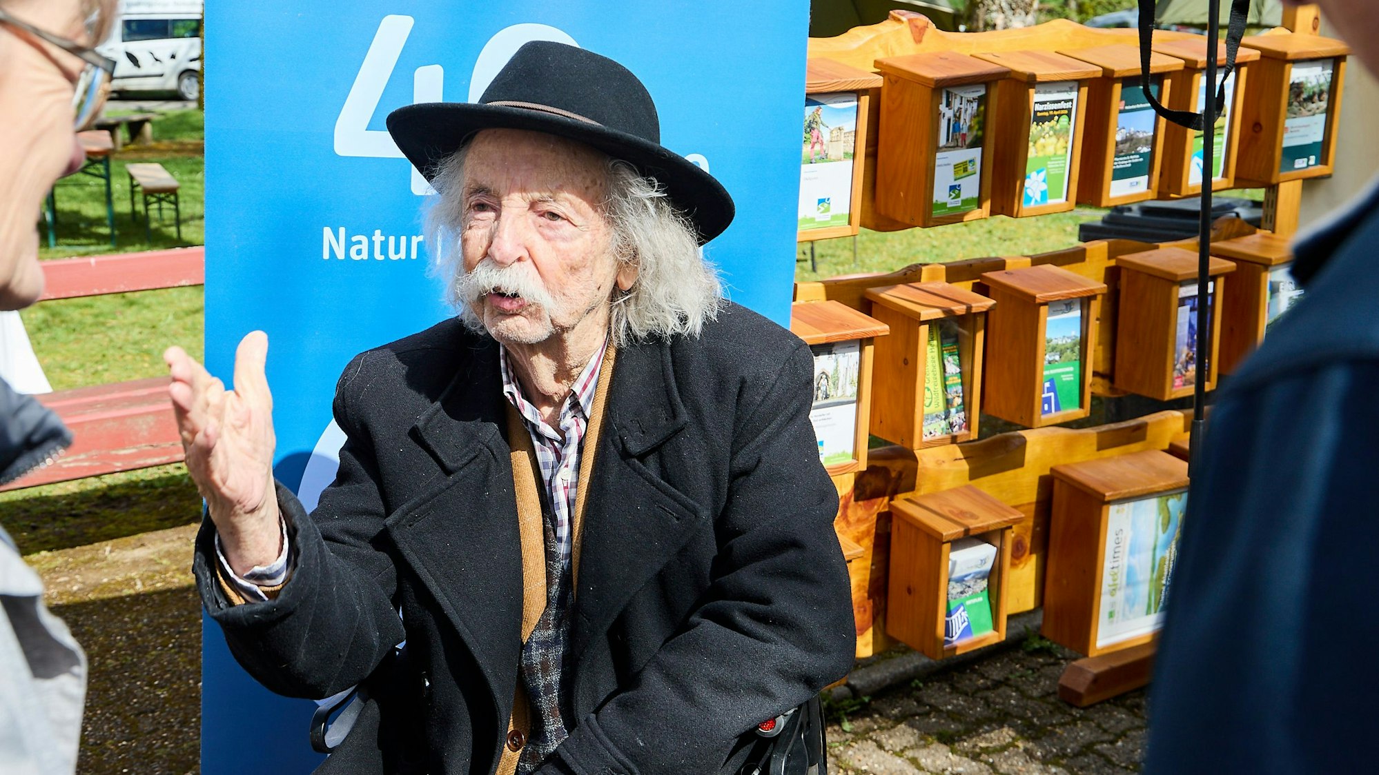 Jean Pütz sitzt auf einem Stuhl und gestikuliert mit einer Hand.