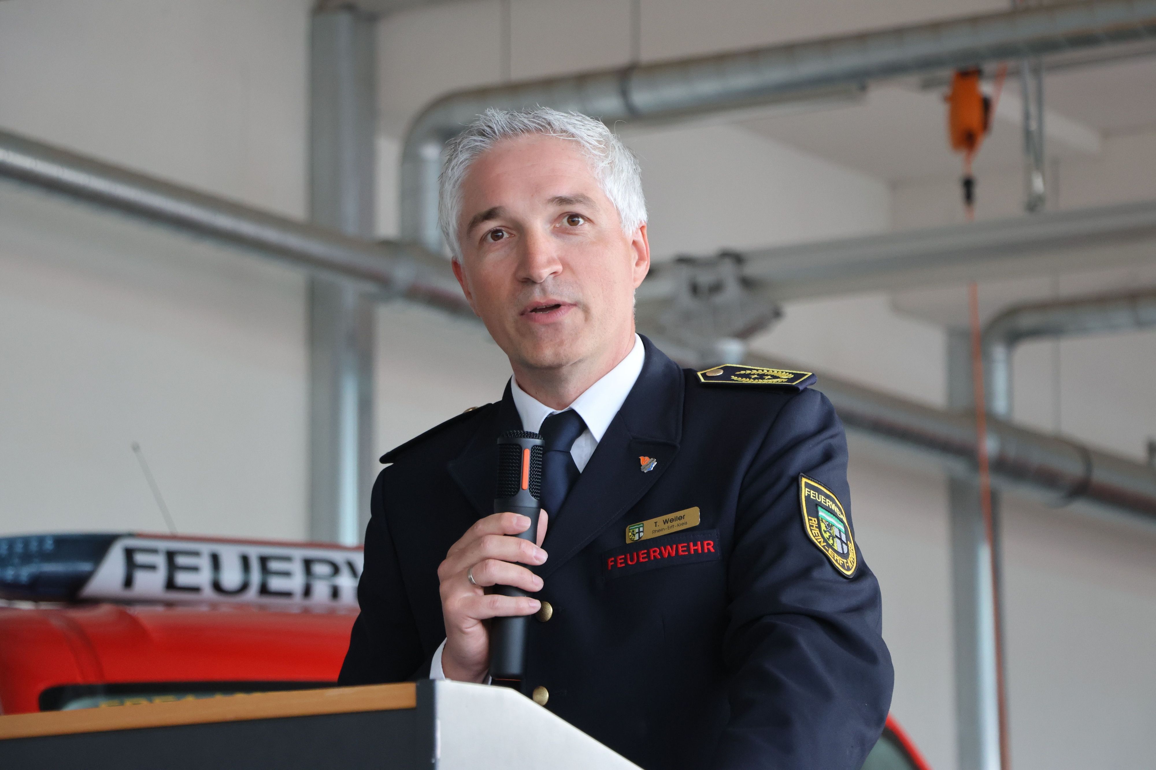Das Bild zeigt den Kreisbrandmeister Thomas Weiler am Mikrofon.