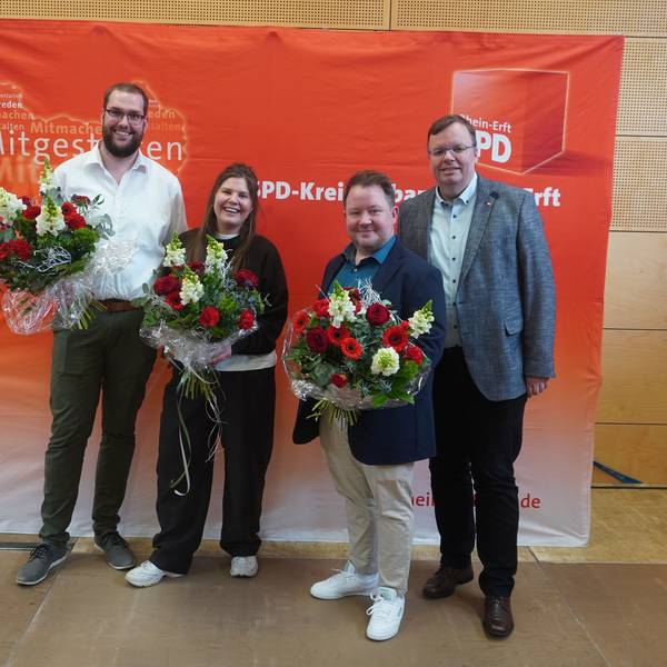 Das Bild zeigt die Kandidaten mit Herrwegen vor einem SPD-Banner. Die Kandidaten halten Blumensträuße.