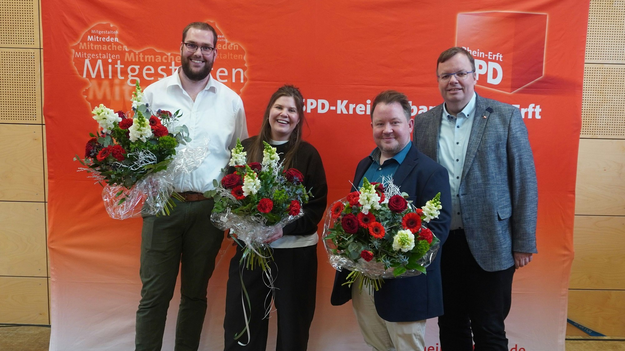 Das Bild zeigt die Kandidaten mit Herrwegen vor einem SPD-Banner. Die Kandidaten halten Blumensträuße.