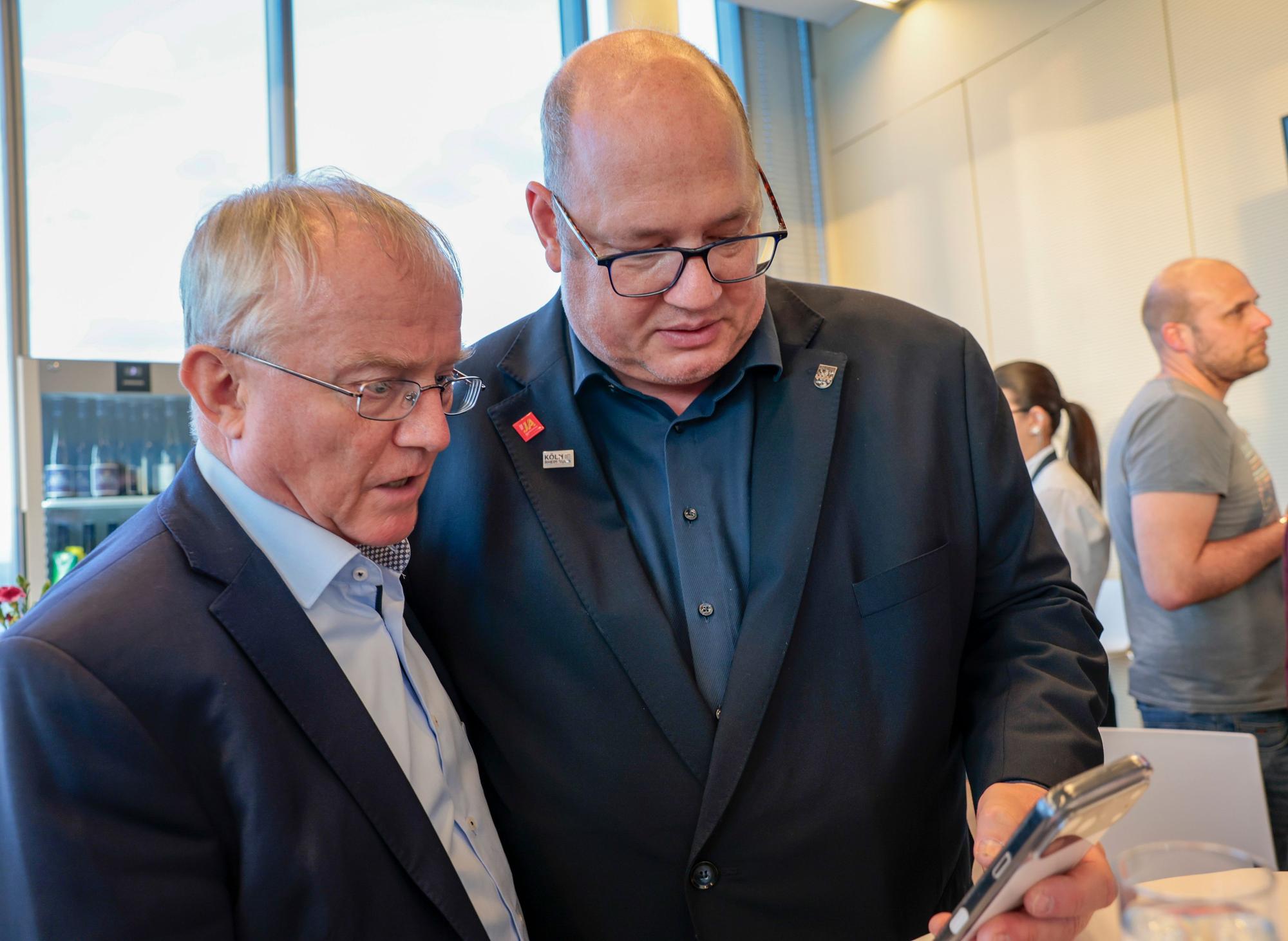 Rüdiger Scholz (MDL, CDU) und Leverkusens Oberbürgermeister Stefan Hebbel verfolgen die Ergebnisse über ihr Smartphone.