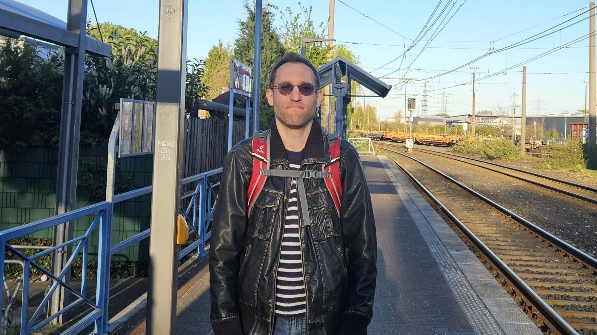 Das Bild zeigt den Fahrgast an der Haltestelle, die Gleise neben sich.
