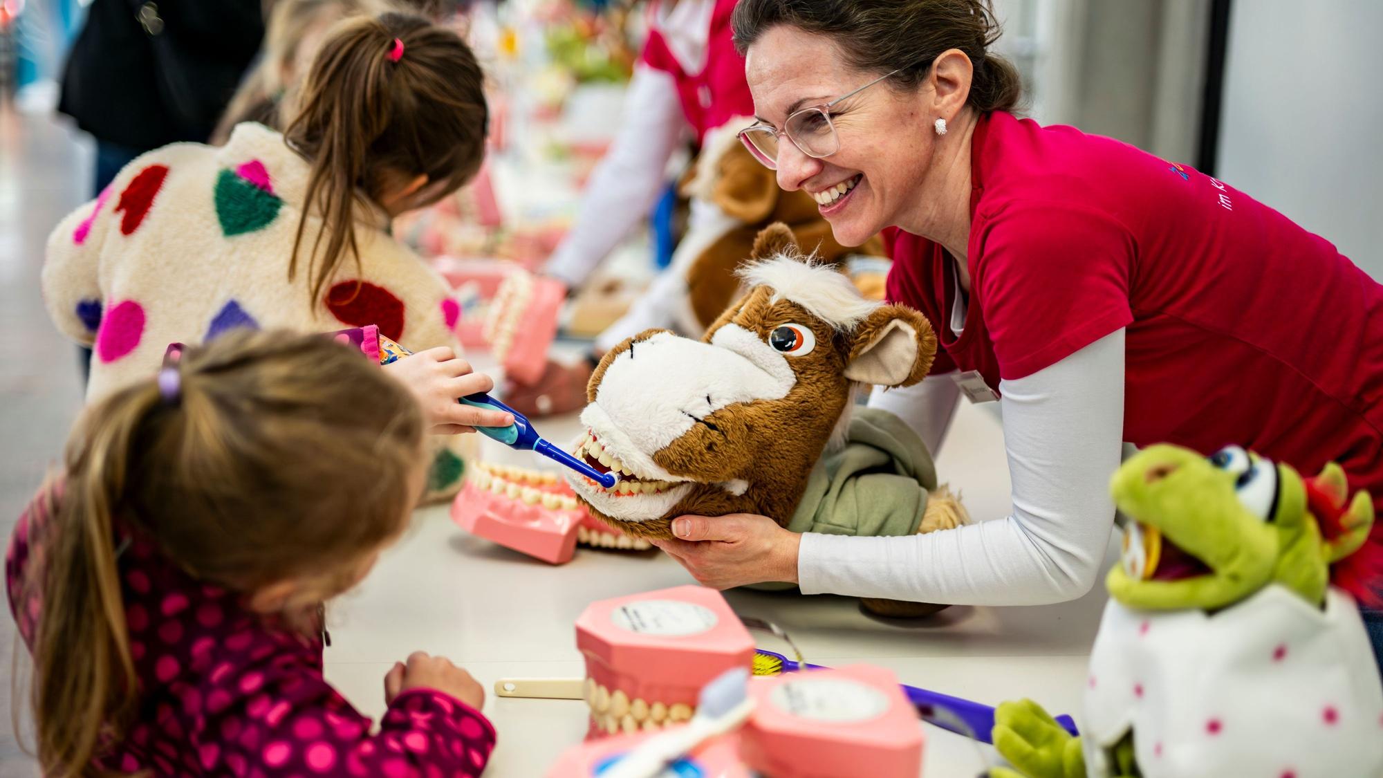 Das Bild zeigt ein Kita-Kind, wie es an einer Handspielpuppe das richtige Zähneputzen übt.