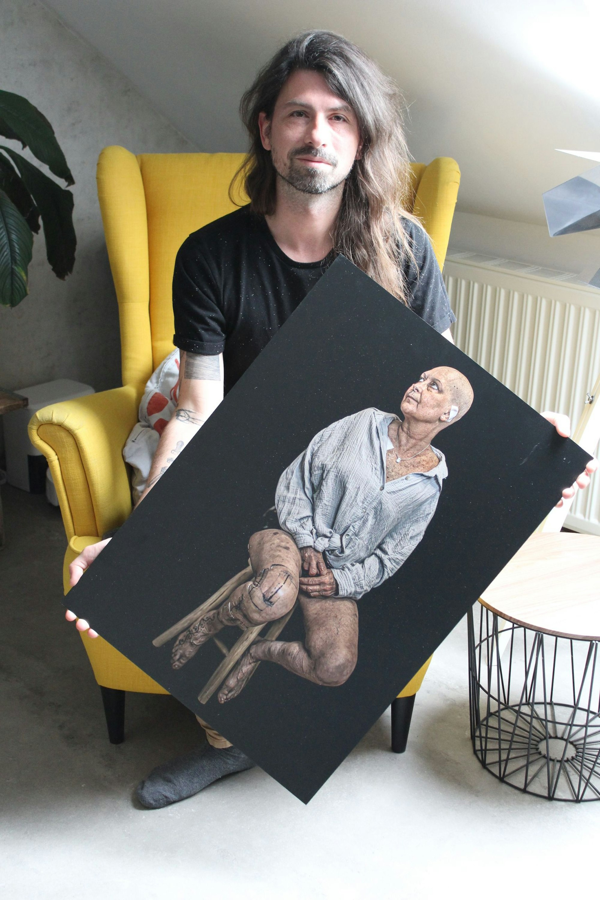 Das Foto zeigt einen Mann, der eine große Fotografie hält.