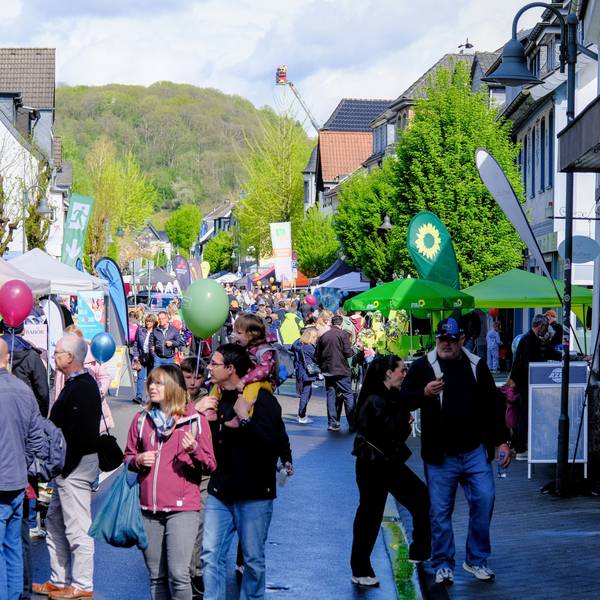 Viele Menschen laufen an Ständen eines Straßenfests vorbei.