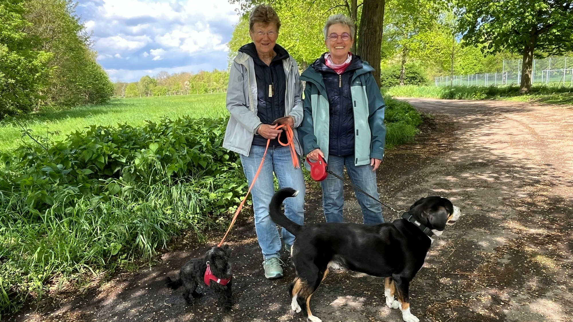 Zwei Frauen stehen mit zwei Hunden auf einem Weg.