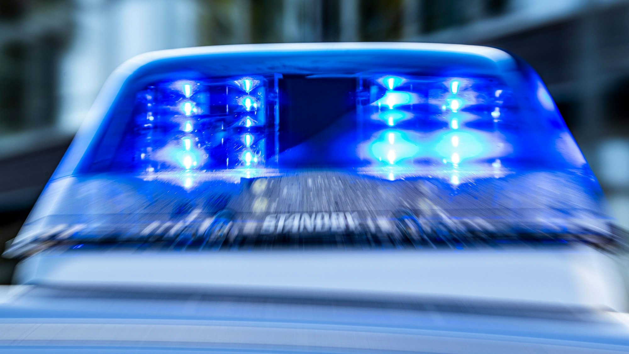Das Blaulicht an einem Polizeiwagen ist eingeschaltet.