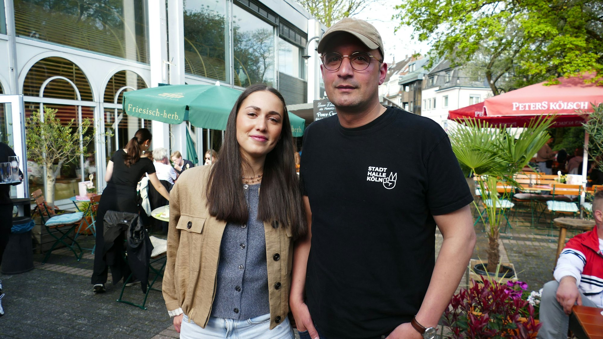 Eine junge Frau steht neben einem Mann mit Kappe.