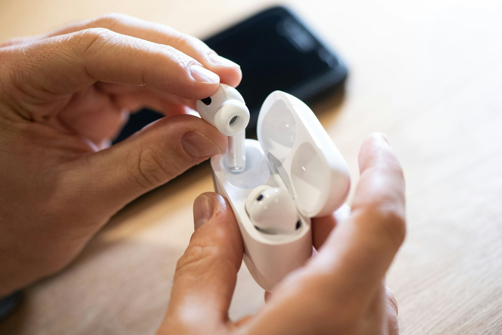 Ein Mann zieht Apple AirPods Pro aus dem Ladecase