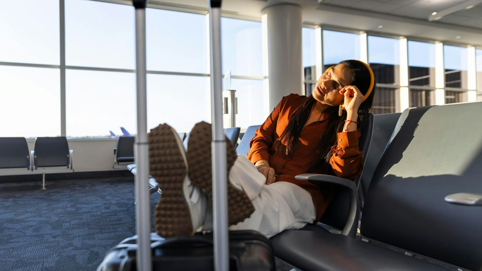 Eine Frau mit Kopfhörern wartet am Gate auf einen Flug