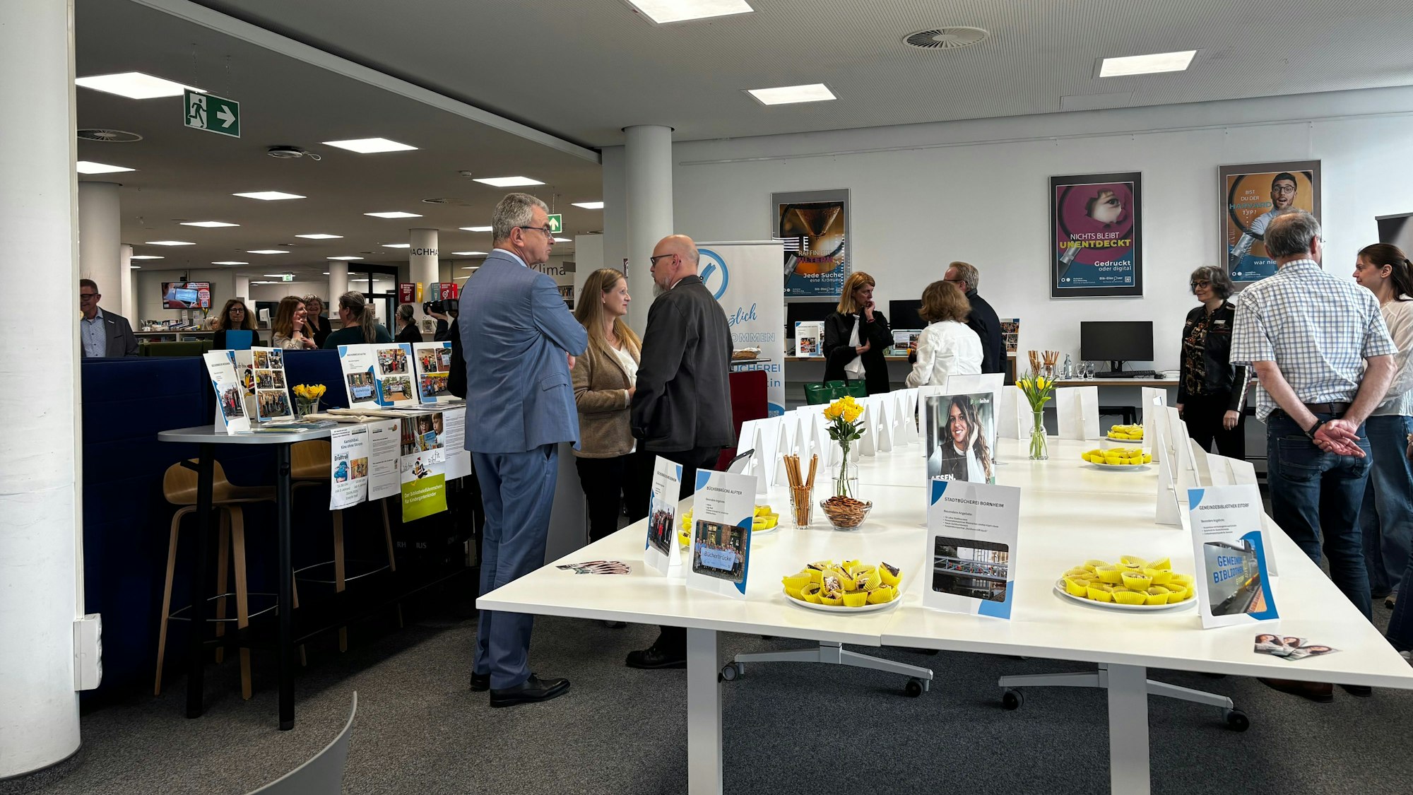Blick in den Raum. Menschen stehen um die Stände der Bibliotheken verteilt.