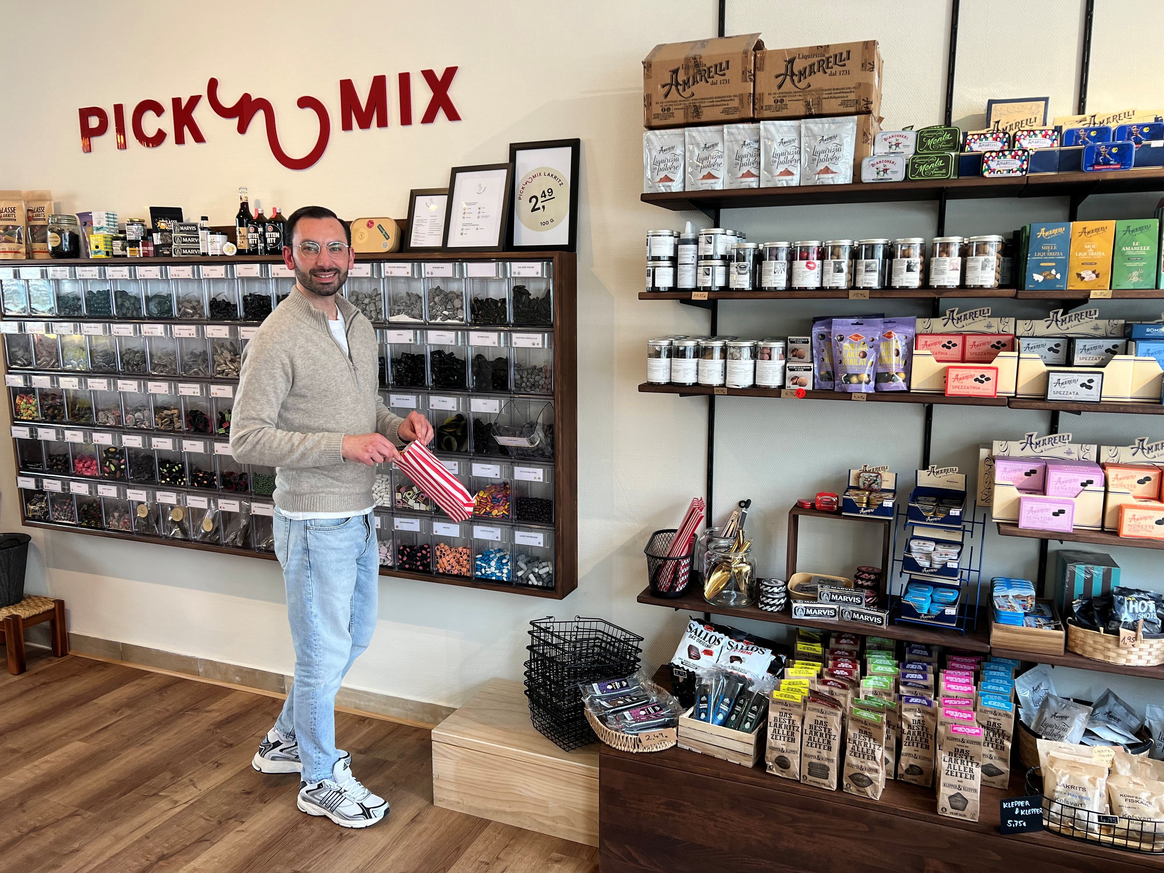 Ein Mann steht vor einer Wand mit vielen verschiedenen Lakritzsorten.