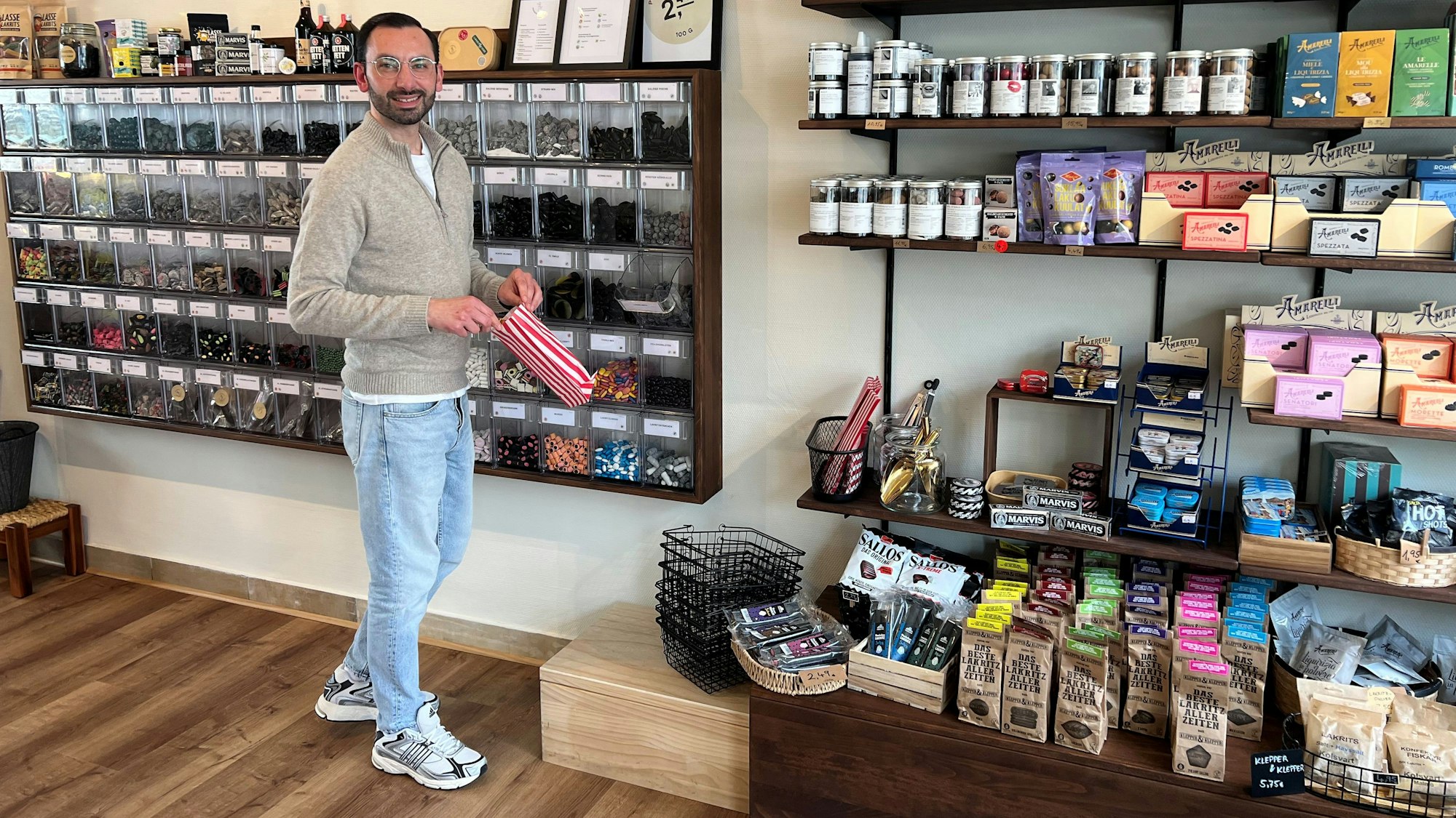 Ein Mann steht vor einer Wand mit vielen verschiedenen Lakritzsorten.