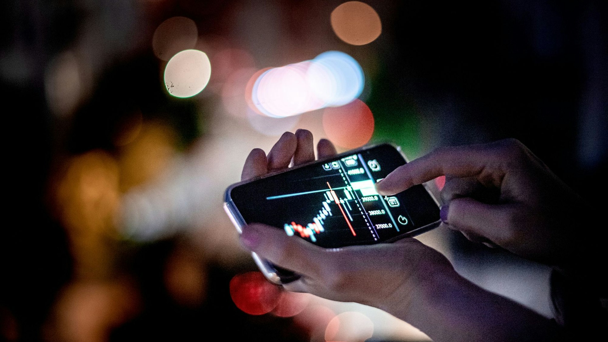 Mann hält ein Smartphone mit einer Trading-App in der Hand