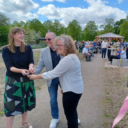 Zwei Frauen und ein Mann halten eine Schere, eine weitere Frau hält Reste eines Eröffnungsbandes, das eben durchgeschnitten wurde.