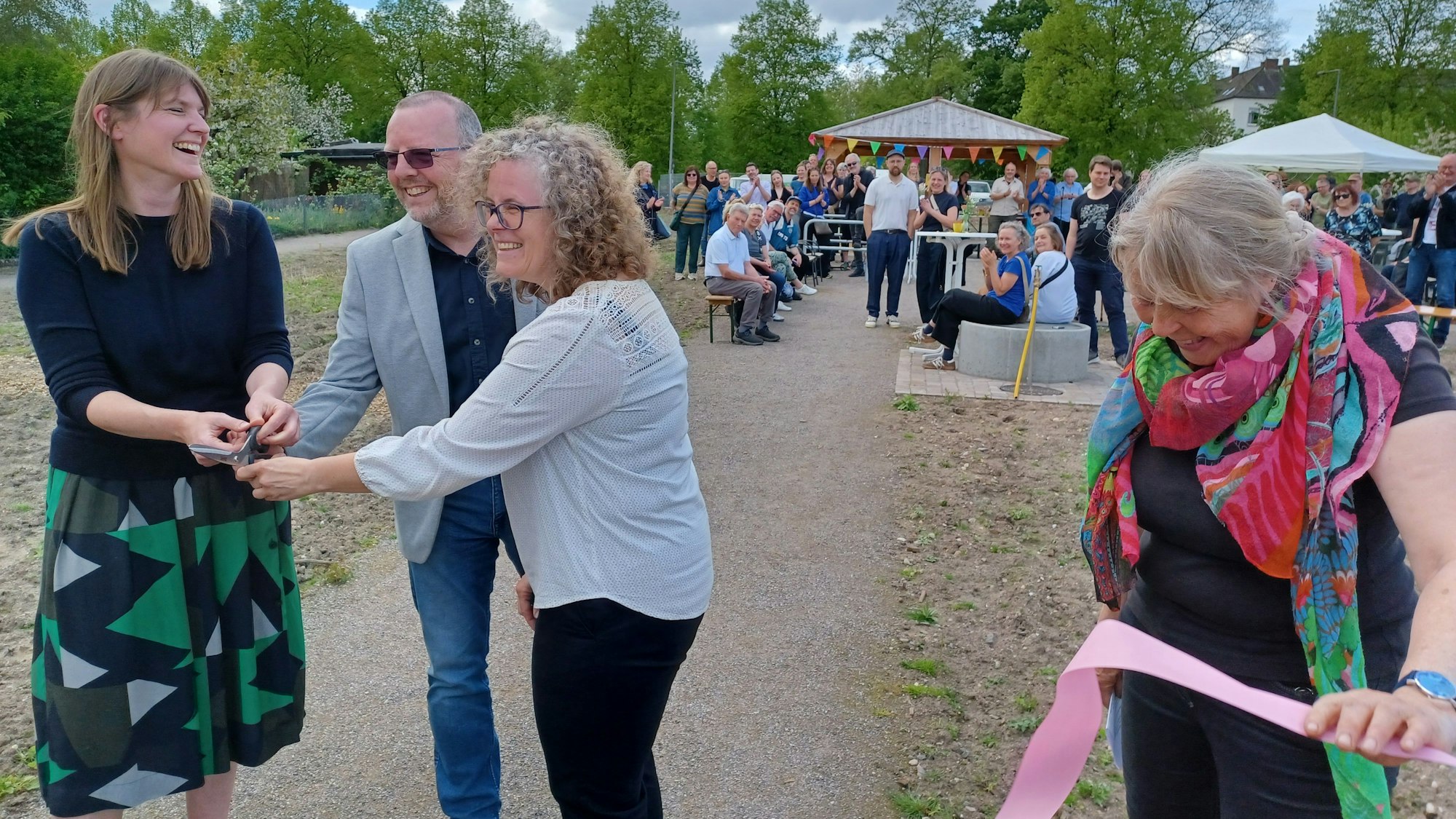 Zwei Frauen und ein Mann halten eine Schere, eine weitere Frau hält Reste eines Eröffnungsbandes, das eben durchgeschnitten wurde.