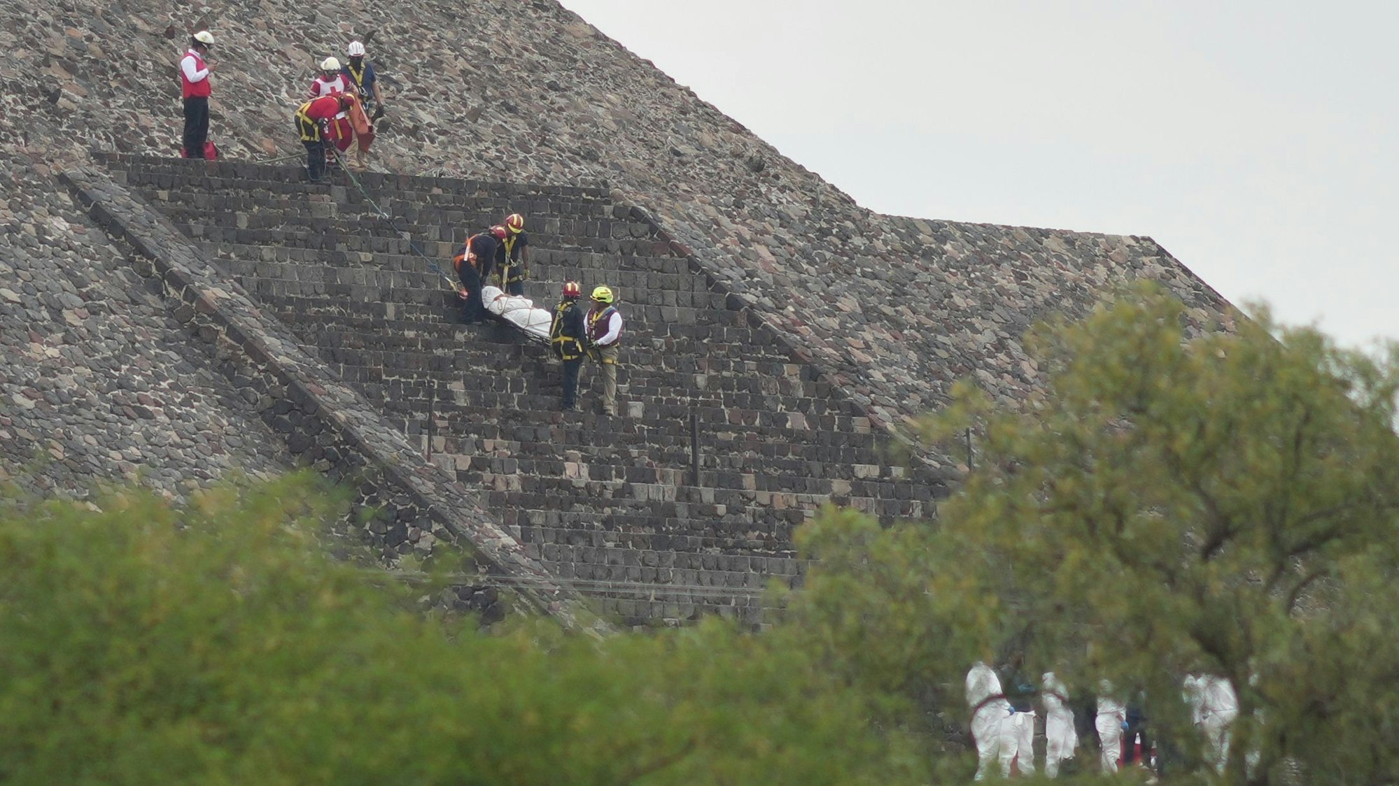 20.04.2026, Mexiko, Teotihuacan: Gerichtsmediziner tragen die Leiche eines Opfers eine Pyramide hinunter, nachdem ein Bewaffneter laut Behörden das Feuer eröffnet hat. Foto: Eduardo Verdugo/AP/dpa +++ dpa-Bildfunk +++