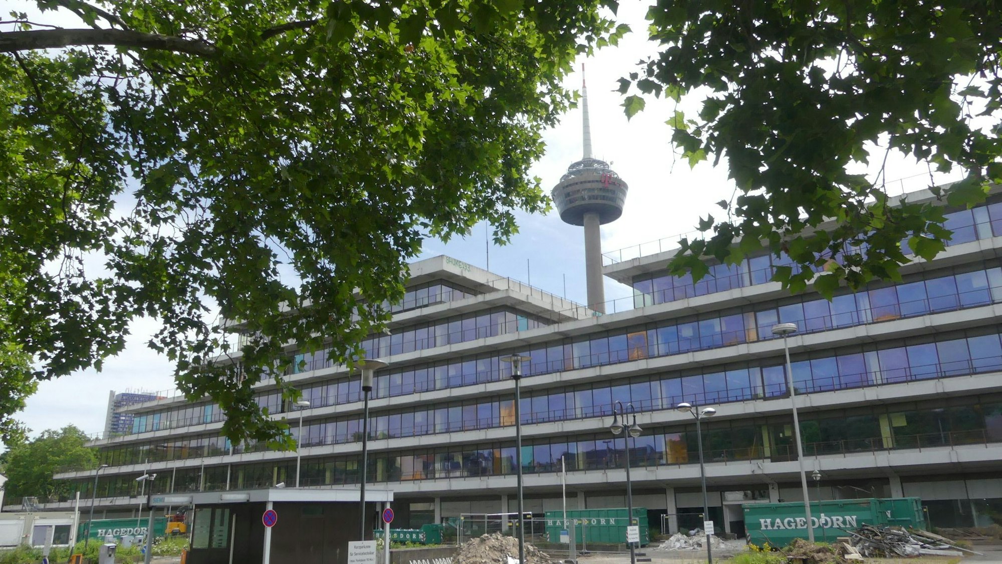 Ein mehrgeschossiges Bürogebäude ist zu sehen, im Hintergrund ragt der Colonius in die Höhe.