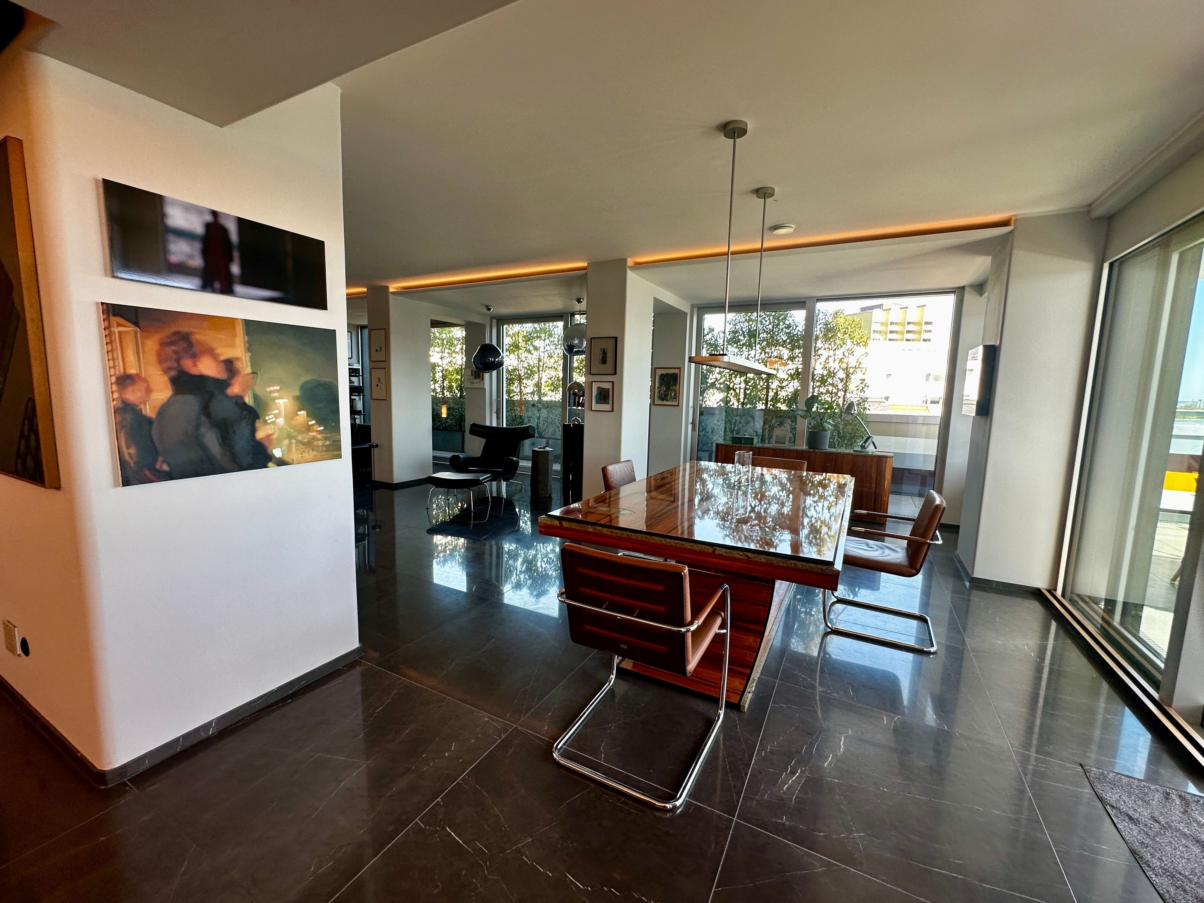 Blick in ein großzügiges offenes Wohnesszimmer mit einem großen blank polierten Tisch.