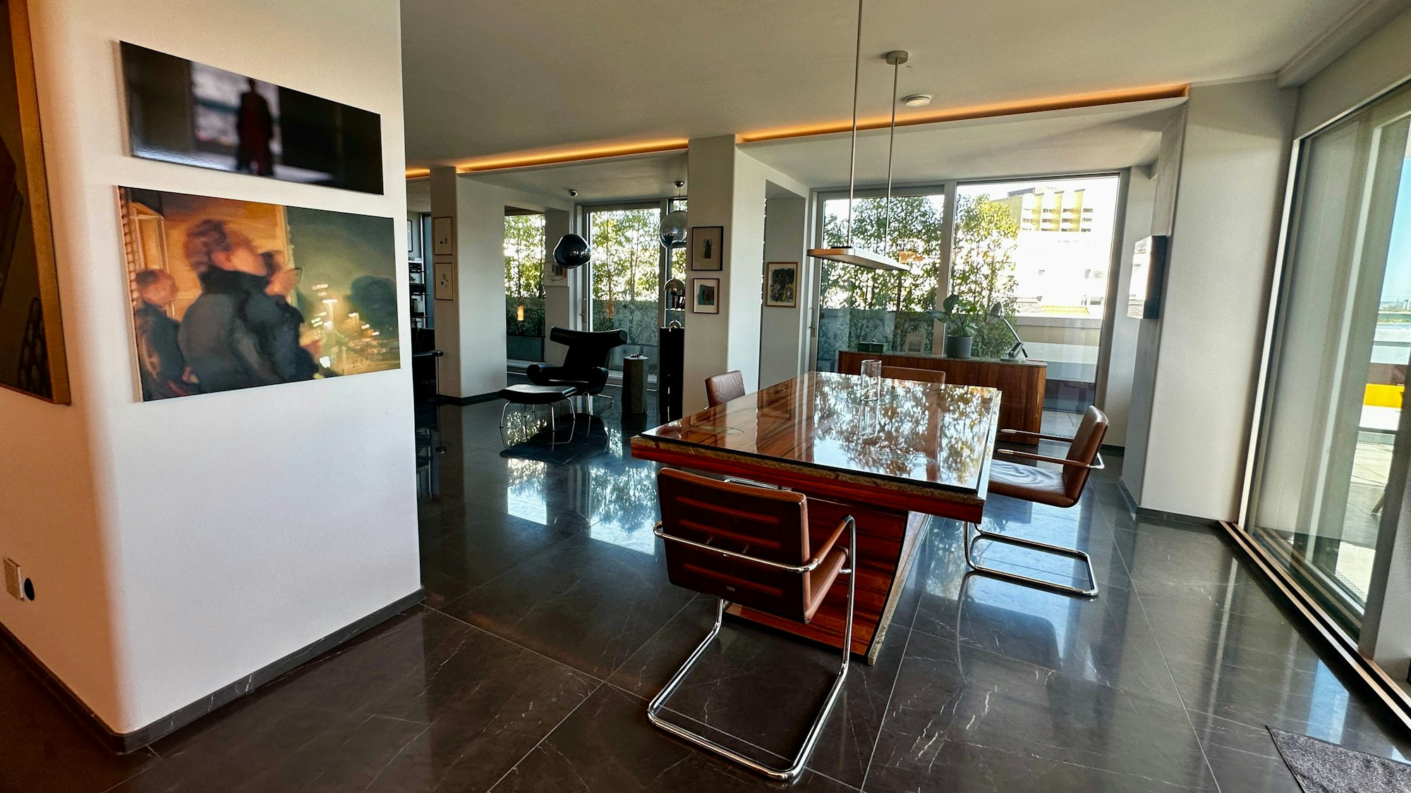 Blick in ein großzügiges offenes Wohnesszimmer mit einem großen blank polierten Tisch.