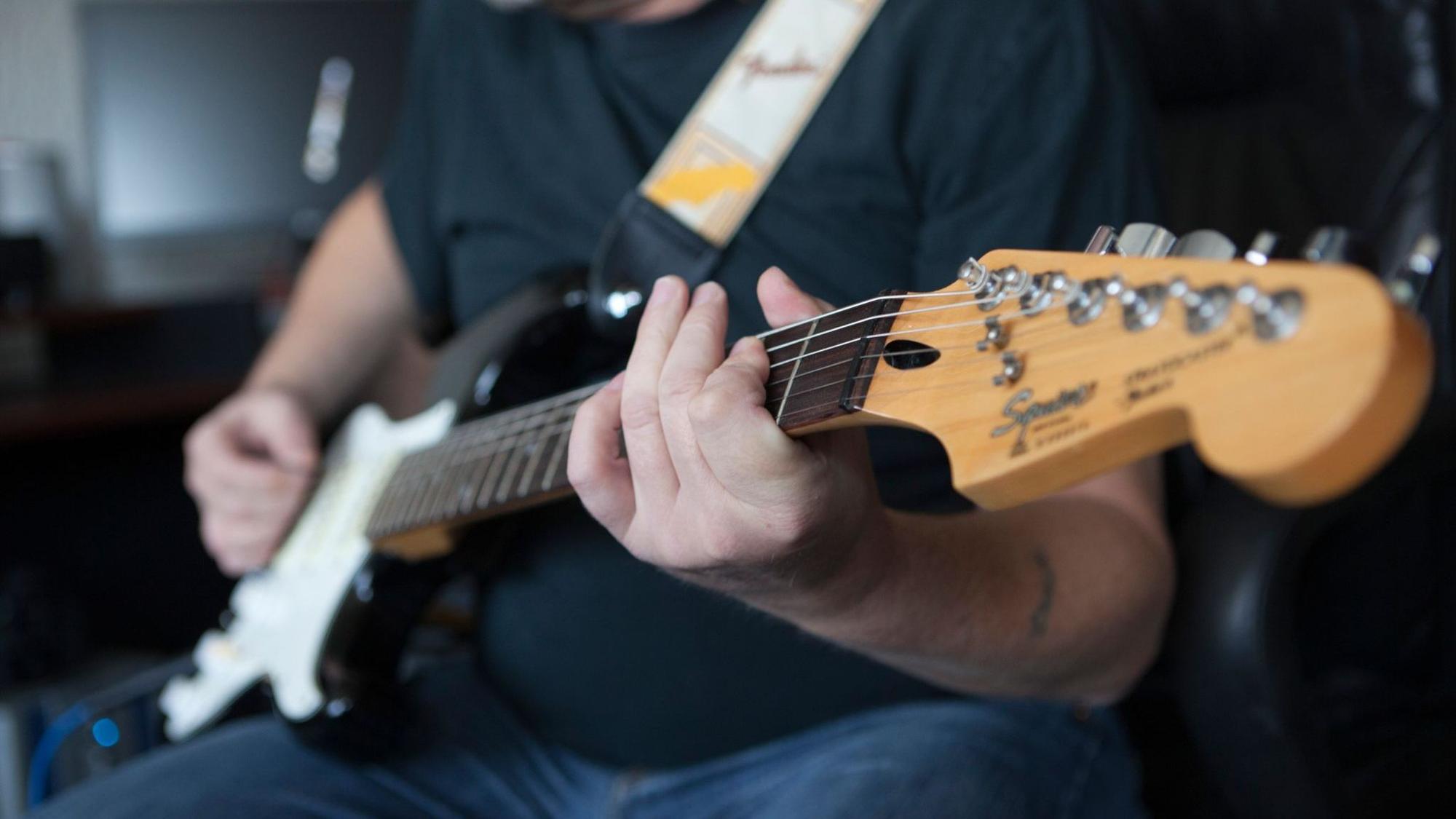 Mann spielt auf einer E-Gitarre