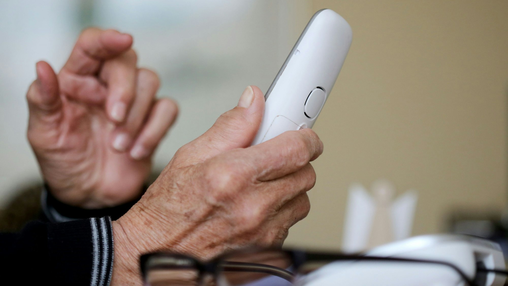 Ein Senior hält einen Telefonhörer in der Hand.