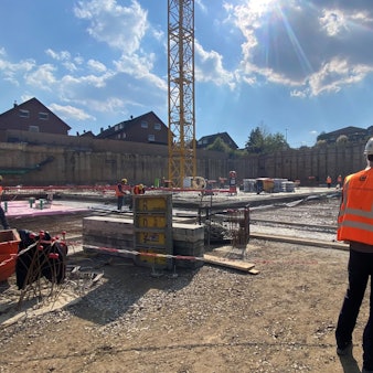 Zu sehen ist die Baustelle, im Vordergrund steht ein Arbeiter.