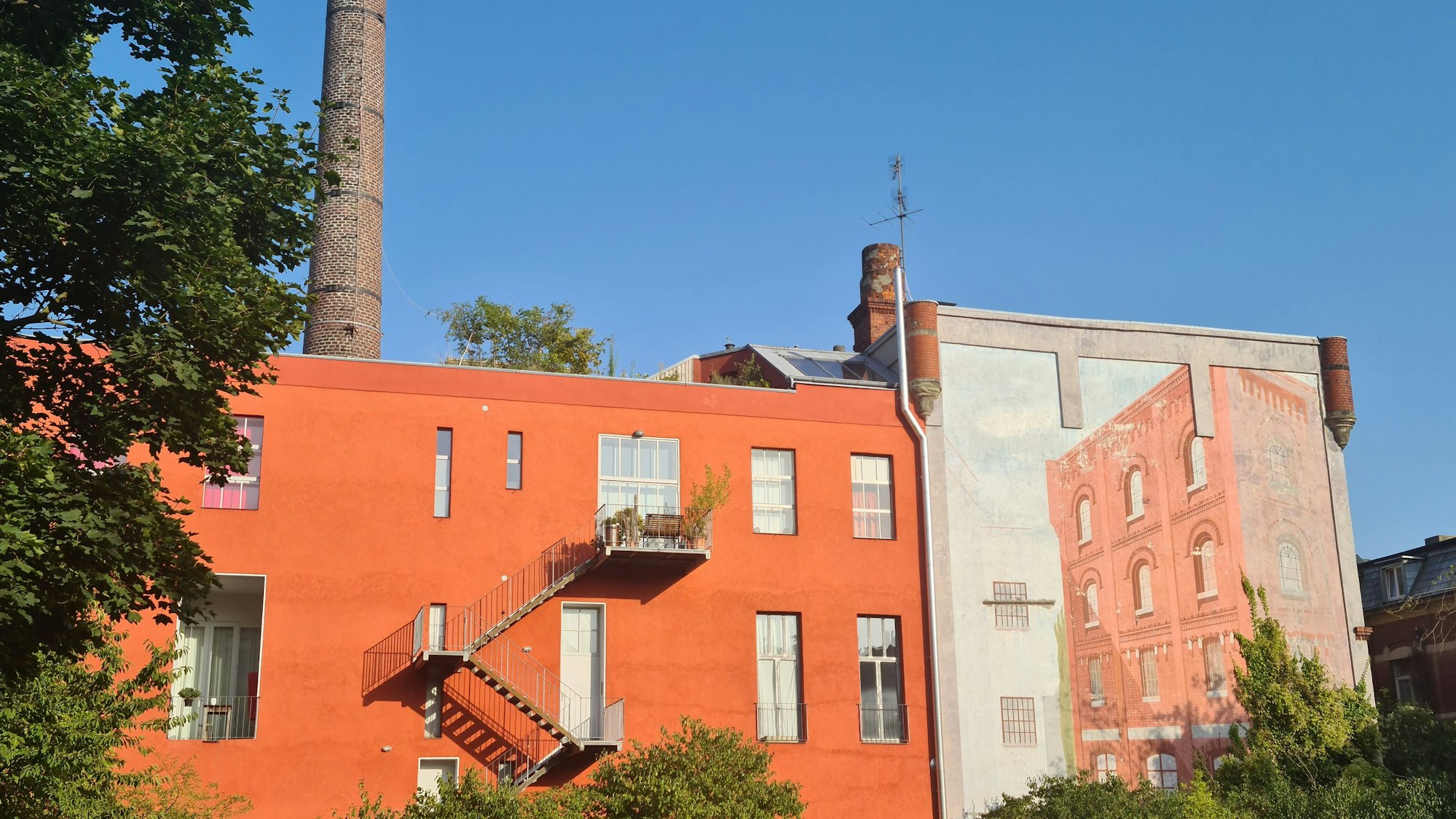 Ein rotes Fabrikgebäude und ein dahinter aufragender Turm