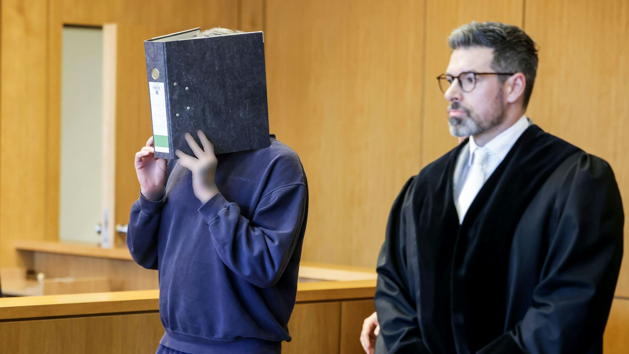 Gegen ihn wird weiter ermittelt: Ulrich S. kommt mit einem Aktenordner vor dem Gesicht im November vergangenen Jahres in den Gerichtssaal. Das Aachener Landgericht hat den Krankenpfleger wegen des Mordes an zehn Patienten zu einer lebenslangen Freiheitsstrafe verurteilt.