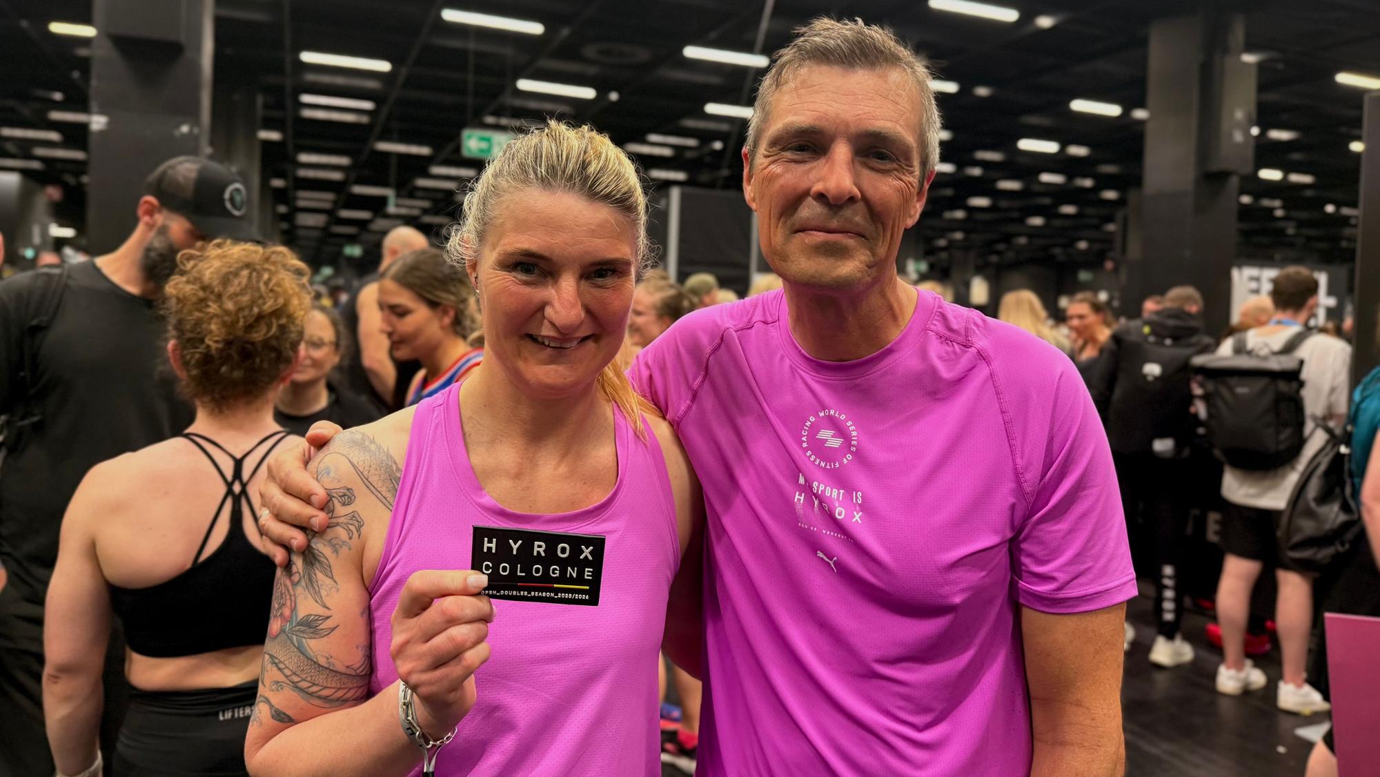 Manuela Petruk und Stefan Kauhardt, beide im pinken Sportdress, im Zielbereich des Hyrox in Köln