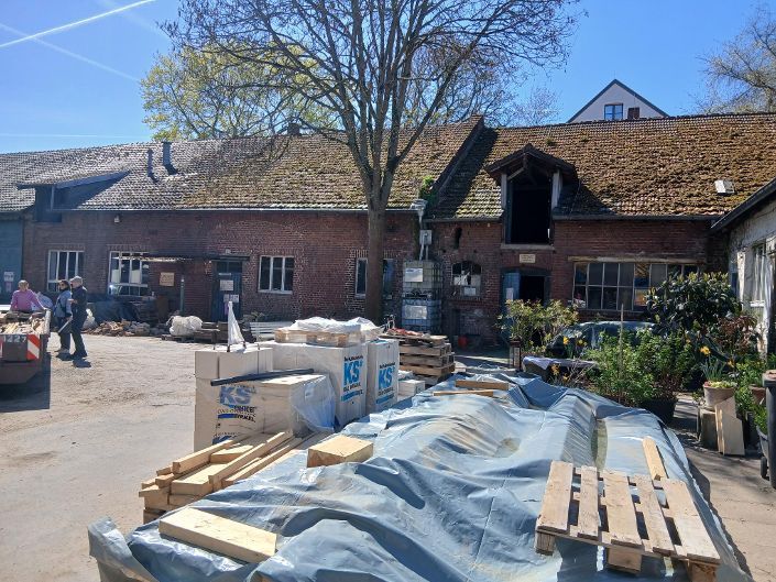 Baumaterial ist auf dem Hof eines Backsteingebäudes gelagert.