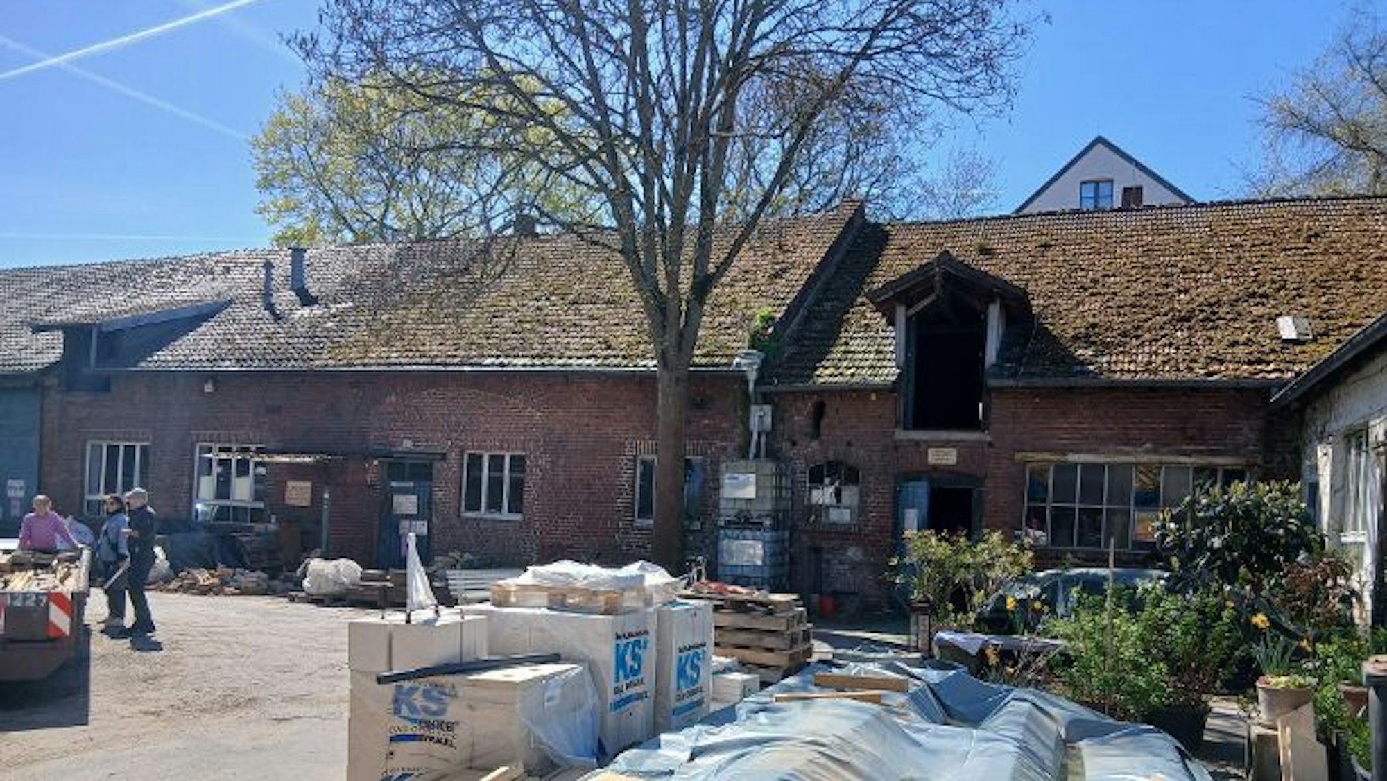 Baumaterial ist auf dem Hof eines Backsteingebäudes gelagert.