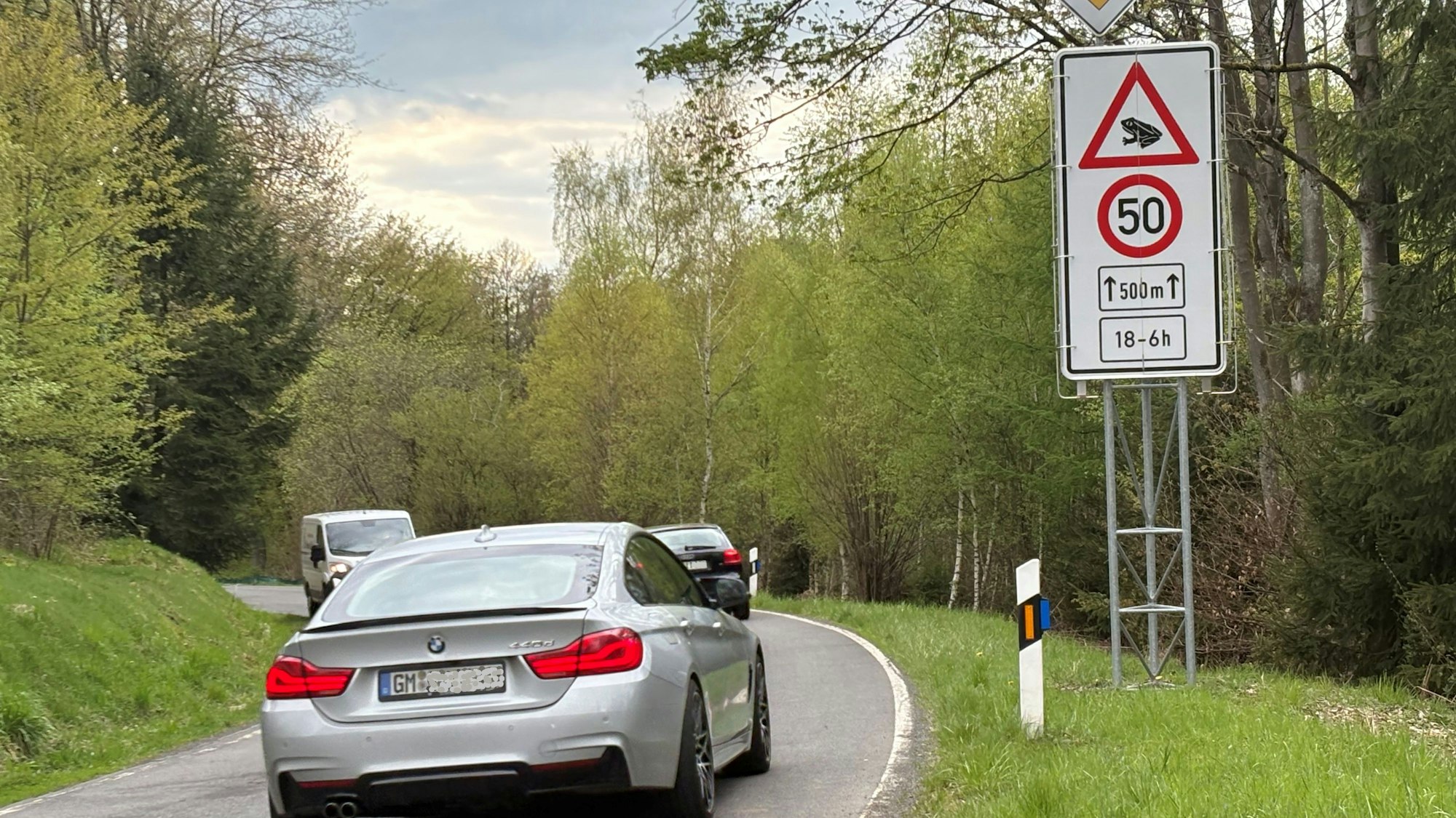Das Foto zeigt eine Straßenszene von der L198 in Nümbrecht. Am Rand sieht man die Beschilderung, die mit verweis auf Amphibienwanderung die Höchstgeschwindigkeit im Zeitraum zwischen 18 und sechs Uhr auf 50 Stundenkilometer beschränkt.