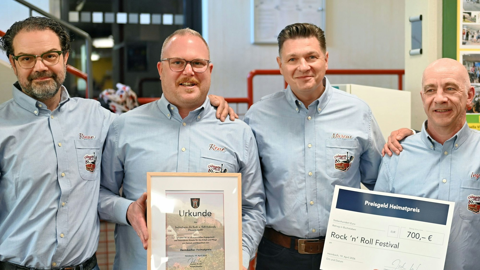 Die vier Geehrten stehen nebeneinander und tragen blaue Hemden.
