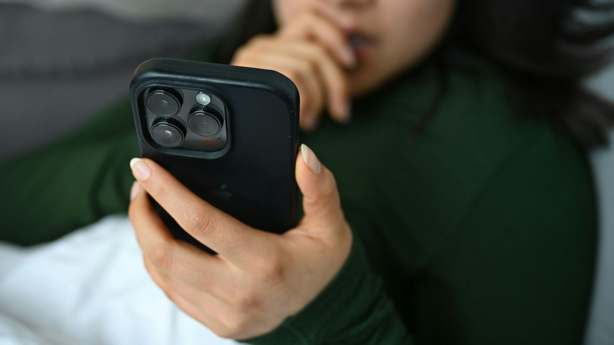 Eine Frau schaut auf dem Sofa auf ihr Handy