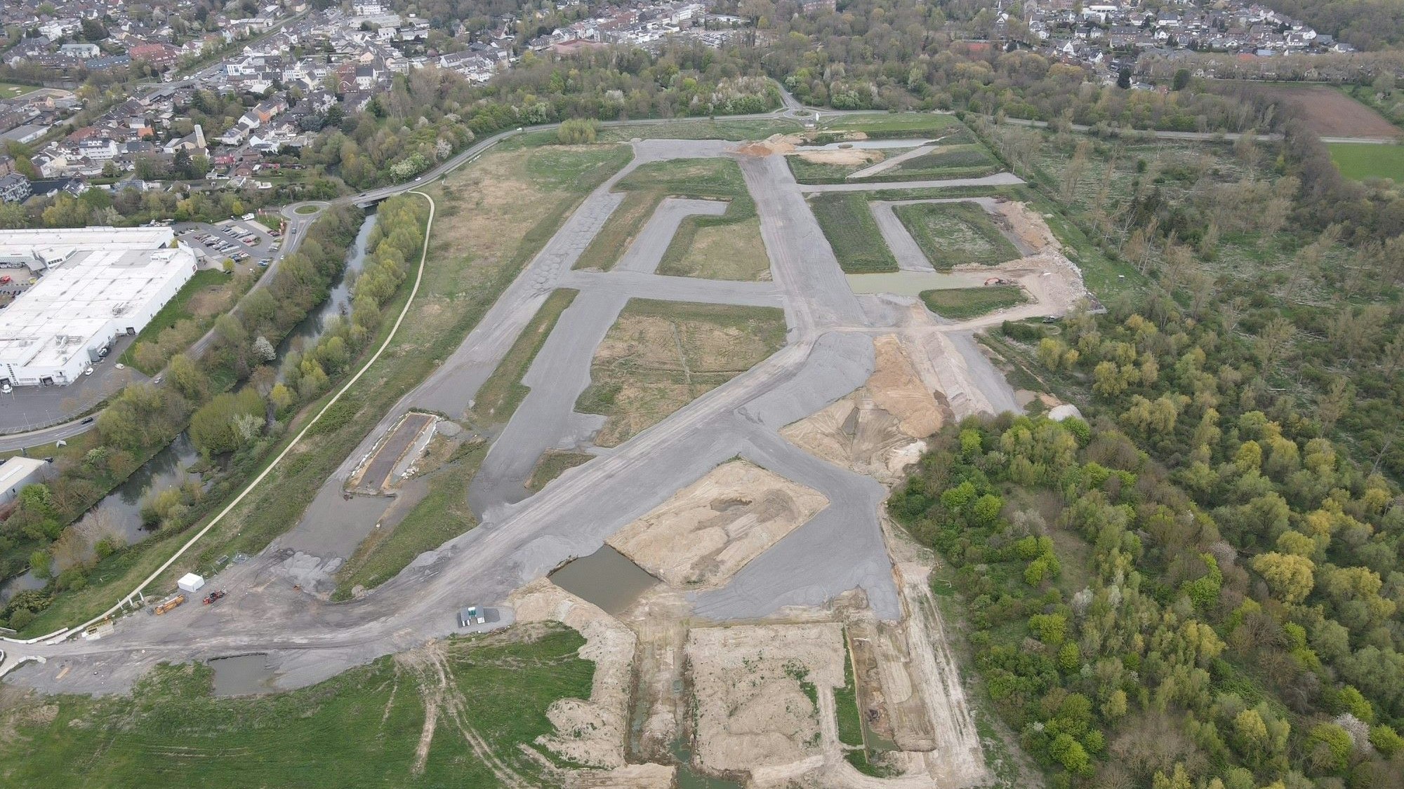 Zu sehen ist ein Luftbild, das graue Aschehalden in einem geplanten Neubaugebiet zeigt.