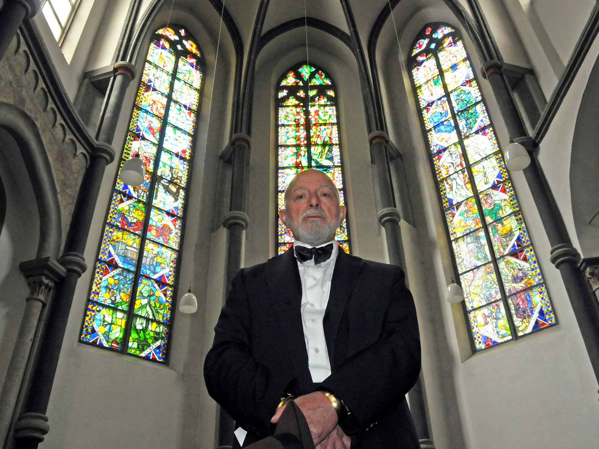 Der Künstler Markus Lüpertz posiert in Köln in der Kirche St. Andreas vor nach seinen Entwürfen gestalteten Fenstern.