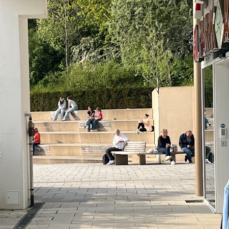 Menschen sitzen zu zweit oder zu dritt auf den Stufen.