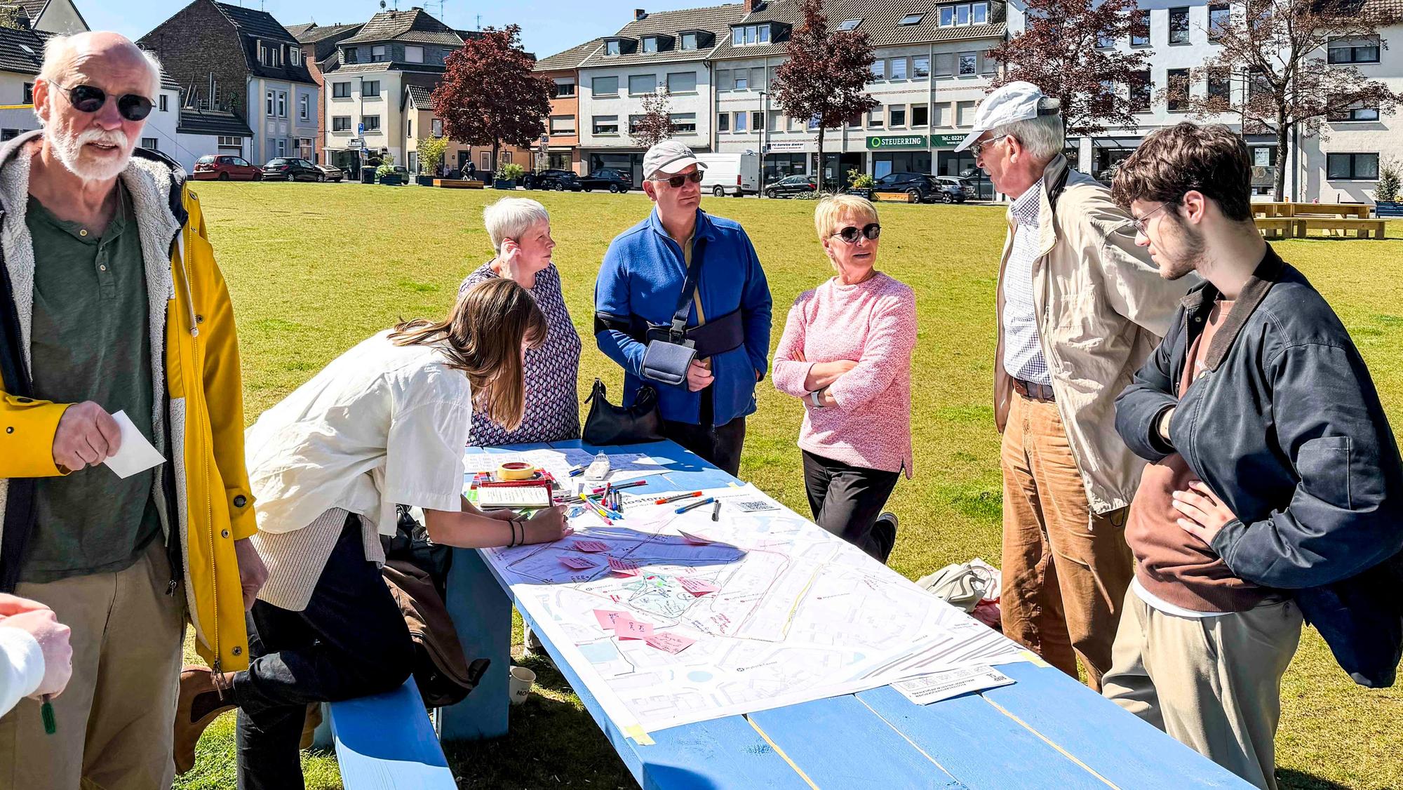 Das Bild zeigt einige Senioren, die um einen Tisch herumstehen und Ideen sammeln.