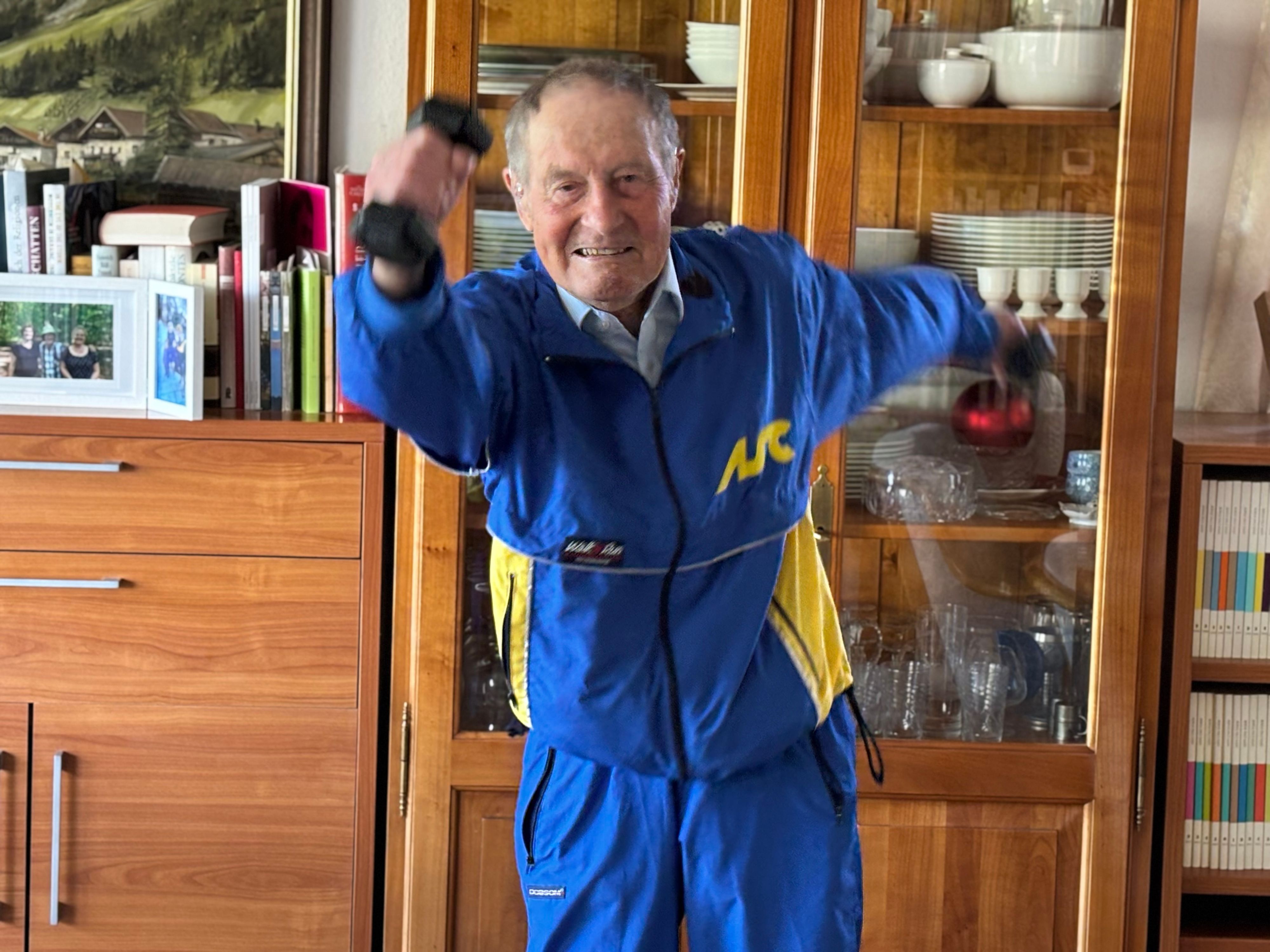 Wilhelm Ehlers trägt einen Trainingsanzug und schwingt Hanteln neben seinem Oberkörper hin und her.