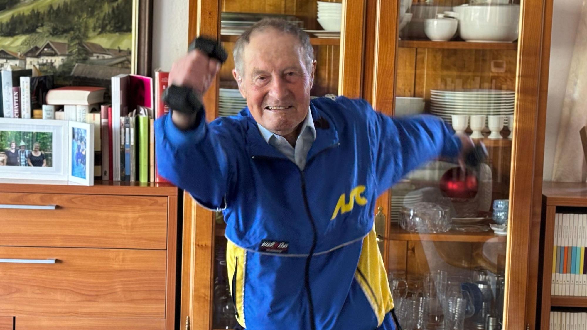 Wilhelm Ehlers trägt einen Trainingsanzug und schwingt Hanteln neben seinem Oberkörper hin und her.