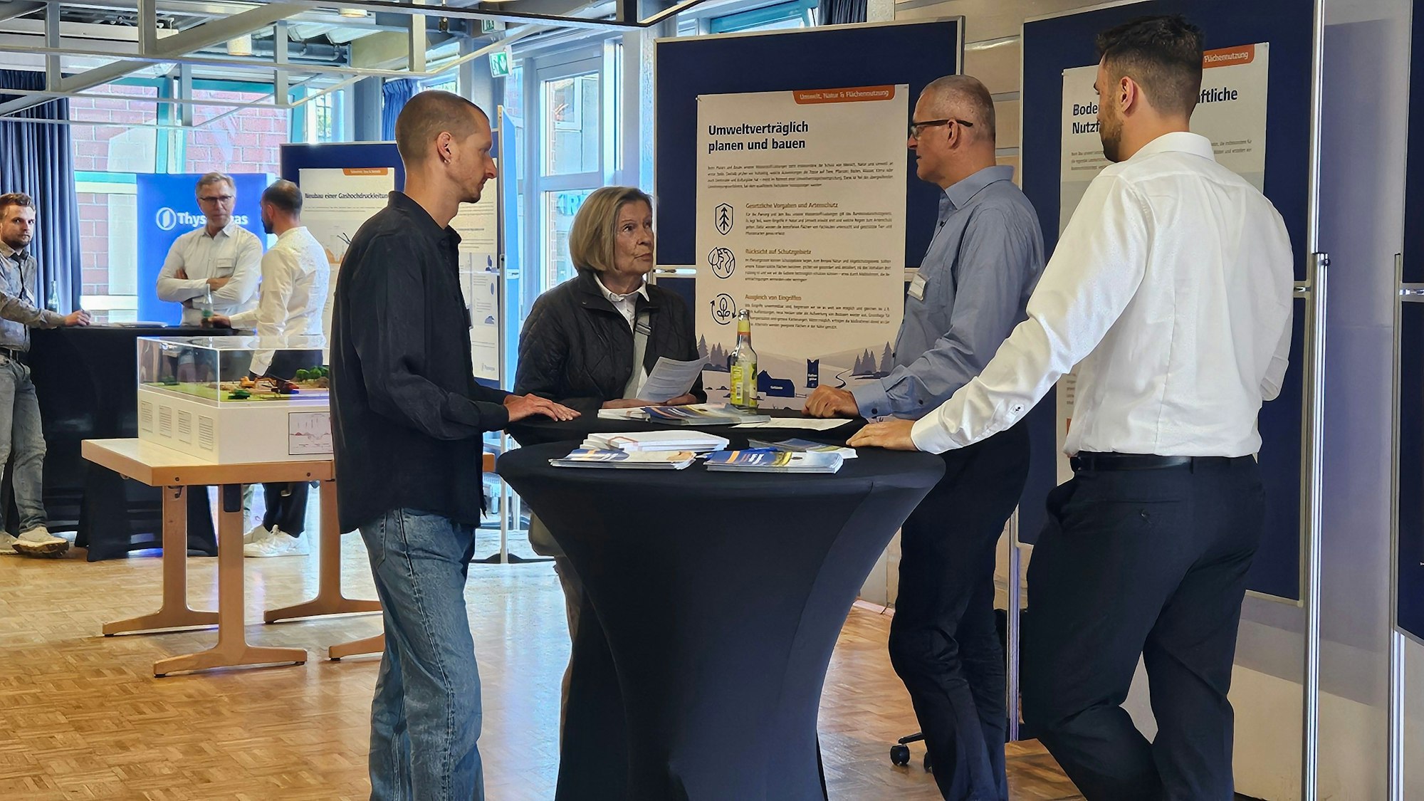 Das Foto zeigt Menschen an einem Stehtisch vor Informationstafeln im Bürgerhaus.