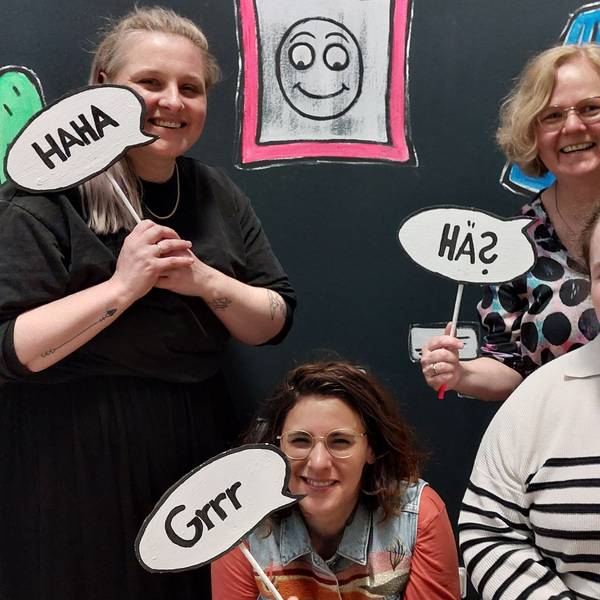 Vier Frauen halten Comicsprechblasen an Holzstäben.
