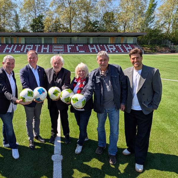 Das Foto zeigt Vertreterinnen und Vertreter der Stadt und des FC Hürth auf dem Kunstrasen vor der Tribüne im Salus-Park.