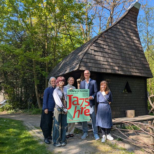 Ein Mann und vier Frauen stehen vor dem Witches Cottage im Park von Schloss Morsbroich