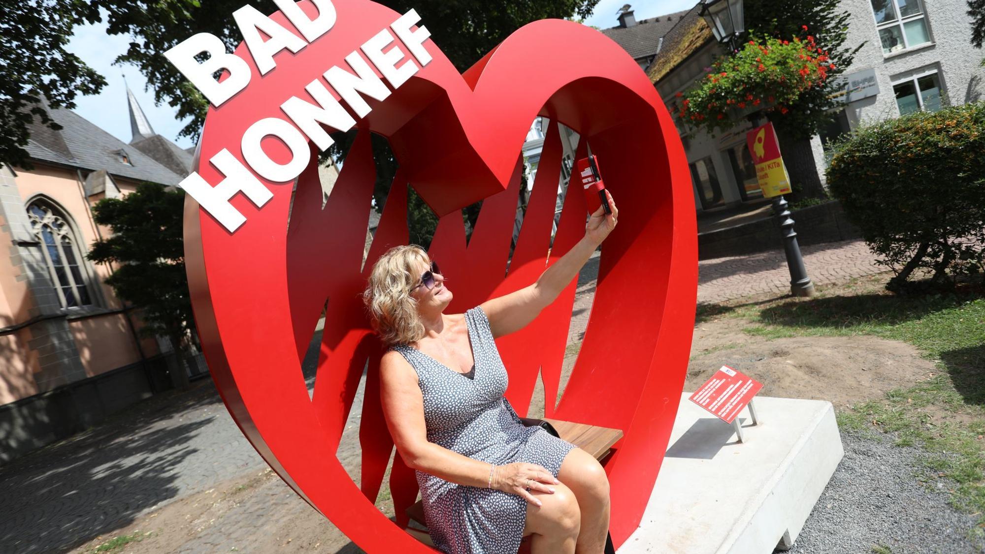 Eine Frau macht ein Selfie in einem Foto-Spot, einem großen roten Herz.
